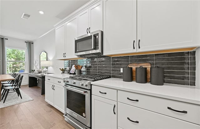 kitchen featuring appliances with stainless steel finishes, visible vents, light countertops, and backsplash