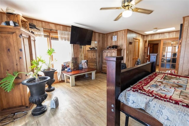 bedroom featuring light hardwood / wood-style flooring, a skylight, and wooden walls