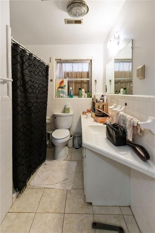 bathroom featuring tile patterned flooring, vanity, toilet, and tile walls