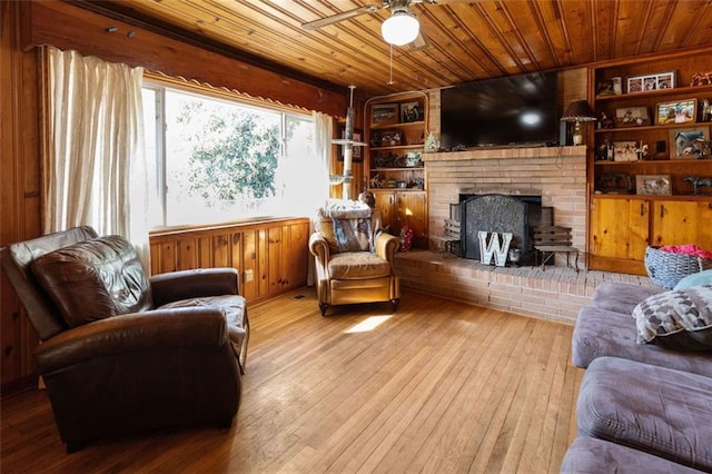 living room featuring a fireplace, light hardwood / wood-style flooring, ceiling fan, wood ceiling, and built in shelves