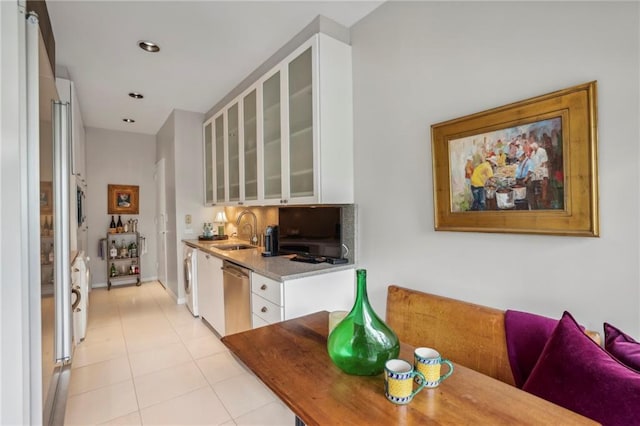 kitchen featuring white cabinets, stainless steel dishwasher, light stone countertops, and sink