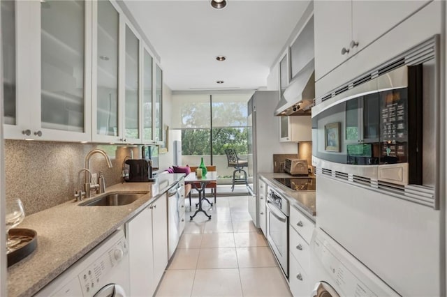 kitchen featuring white cabinets, sink, wall chimney exhaust hood, light tile patterned floors, and appliances with stainless steel finishes