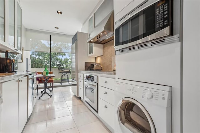 laundry room with stacked washer / dryer and light tile patterned flooring