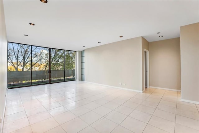 empty room with floor to ceiling windows and light tile patterned flooring