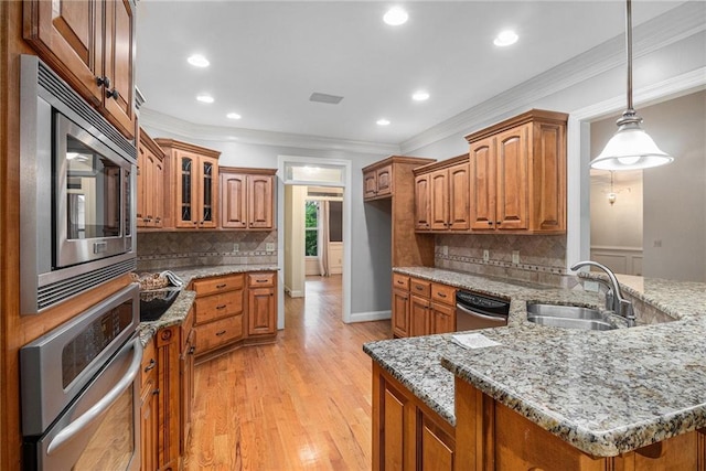 kitchen featuring stainless steel appliances, brown cabinetry, a sink, ornamental molding, and recessed lighting