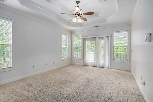 carpeted empty room with ceiling fan, baseboards, ornamental molding, and a raised ceiling