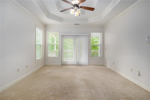 empty room with ceiling fan, carpet flooring, a tray ceiling, ornamental molding, and baseboards