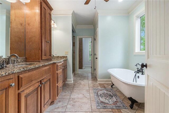 bathroom featuring ceiling fan, a freestanding tub, vanity, crown molding, and baseboards