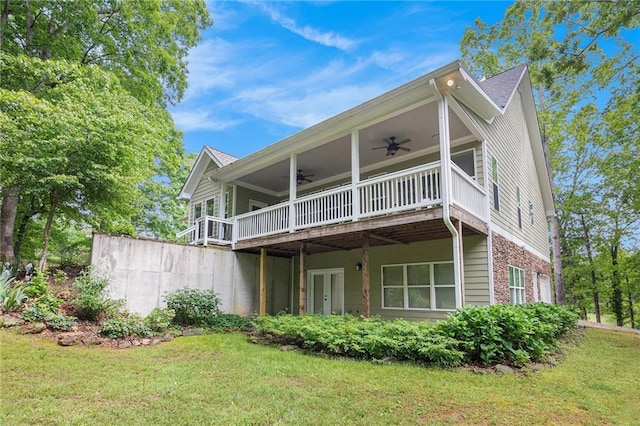 back of property with a ceiling fan, a deck, a lawn, and brick siding