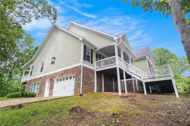 view of side of home featuring stone siding, a garage, a deck, and stairs