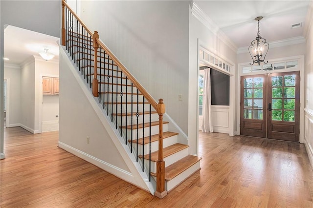 foyer featuring a chandelier, stairway, crown molding, and light wood finished floors