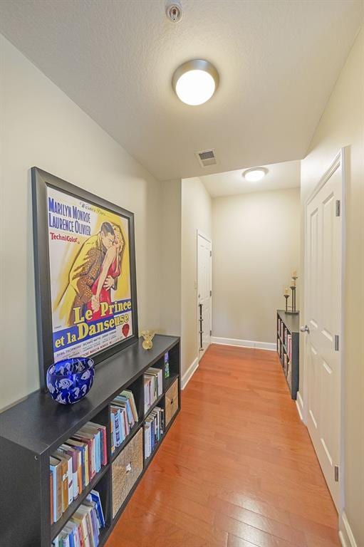 hall with hardwood / wood-style floors and a textured ceiling