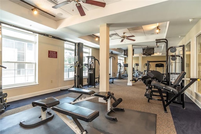 gym featuring a tray ceiling and ceiling fan