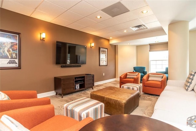 living room featuring a drop ceiling and light carpet