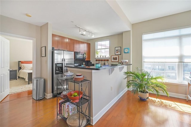 kitchen with stainless steel fridge, kitchen peninsula, tasteful backsplash, a kitchen breakfast bar, and hardwood / wood-style floors