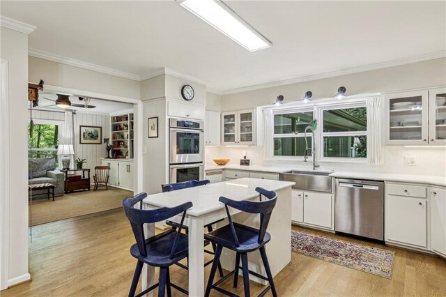 3311 Stillhouse Rd SE, Atlanta, GA 30339 - kitchen with appliances with stainless steel finishes, a sink, a kitchen breakfast bar, white cabinets, and crown molding