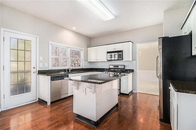 kitchen featuring stainless steel appliances, a center island, sink, and white cabinets