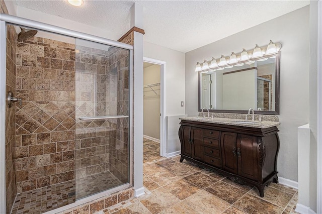 bathroom with vanity, a textured ceiling, and walk in shower