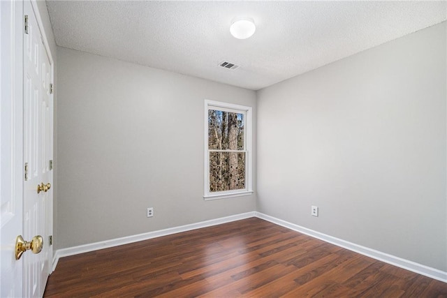 spare room featuring dark wood-type flooring and a textured ceiling