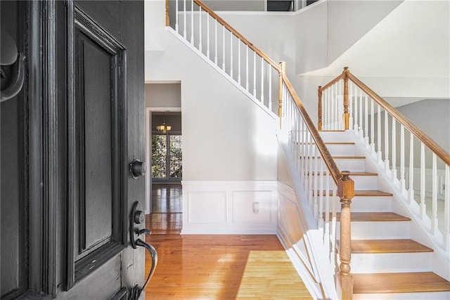 entryway featuring a towering ceiling and light wood-type flooring