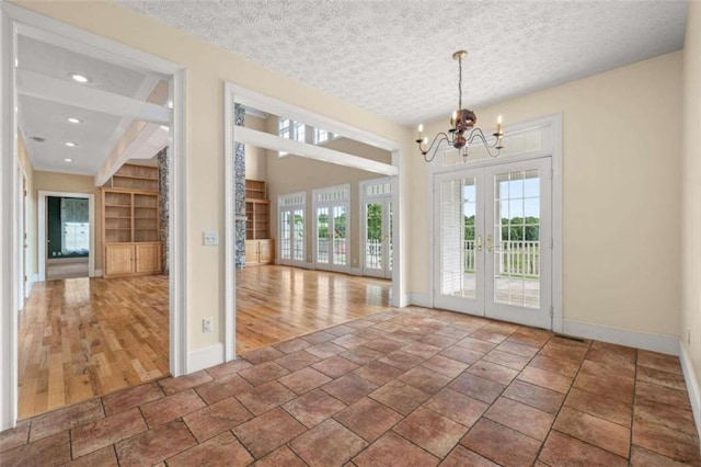 entryway with tile patterned floors, a notable chandelier, a textured ceiling, and french doors