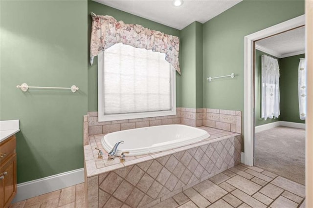 bathroom with crown molding, tile patterned floors, a relaxing tiled tub, and vanity