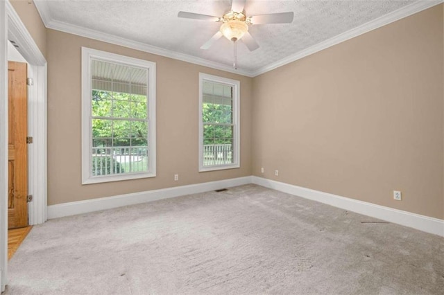 spare room featuring ceiling fan, light carpet, a textured ceiling, and ornamental molding