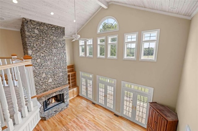 living room with ceiling fan, light wood-type flooring, high vaulted ceiling, and a stone fireplace