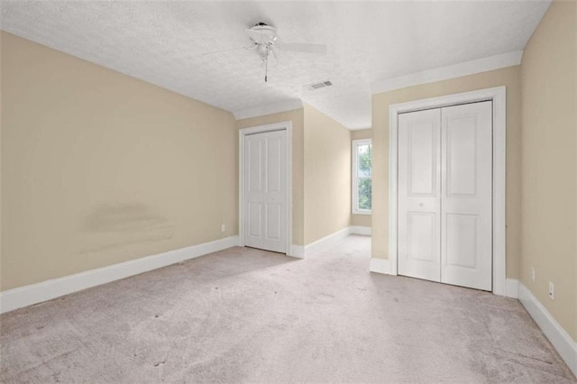 unfurnished bedroom featuring a textured ceiling, ceiling fan, and light colored carpet