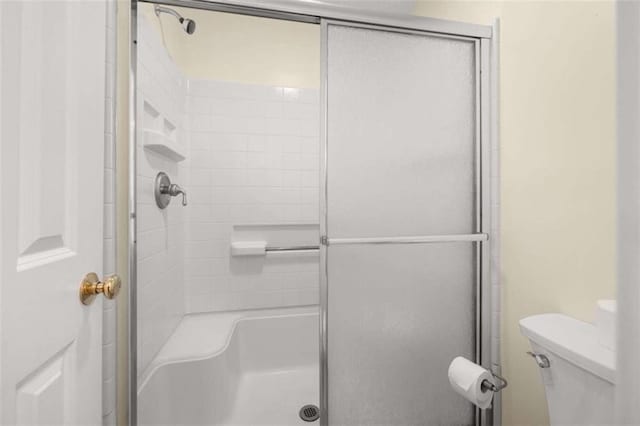 bathroom with a shower with door and toilet