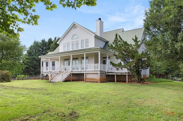 rear view of house featuring a lawn and covered porch