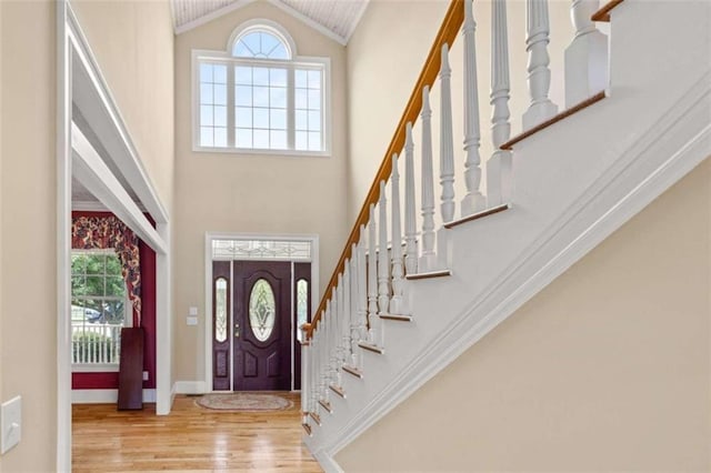 entrance foyer with high vaulted ceiling, light hardwood / wood-style flooring, and crown molding