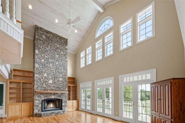 unfurnished living room featuring high vaulted ceiling, a stone fireplace, hardwood / wood-style flooring, wooden ceiling, and ceiling fan