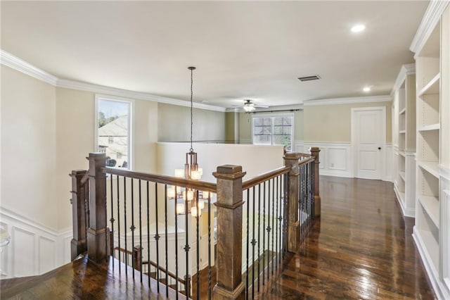 corridor with plenty of natural light, dark hardwood / wood-style flooring, and ornamental molding