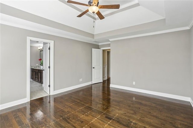 unfurnished bedroom featuring dark wood-type flooring, crown molding, a raised ceiling, and connected bathroom