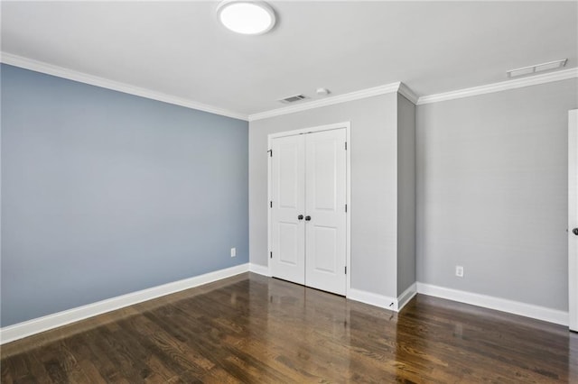 unfurnished bedroom with crown molding, a closet, and dark wood-type flooring