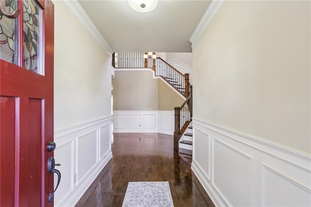 foyer featuring a notable chandelier, dark wood-type flooring, and ornamental molding