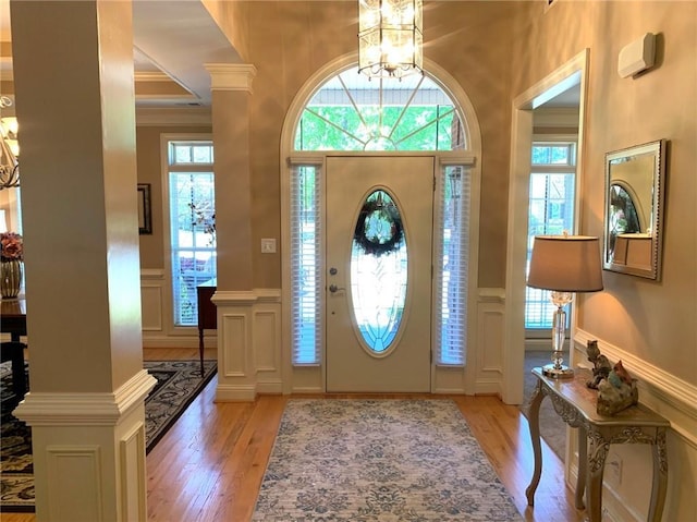 foyer entrance with ornamental molding, light hardwood / wood-style floors, and a notable chandelier