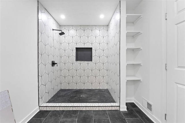 bathroom featuring tiled shower, built in shelves, and tile patterned floors