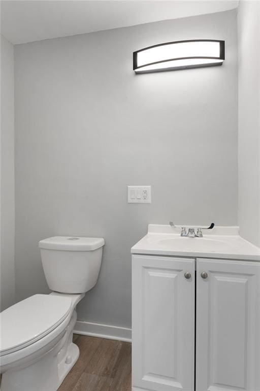 bathroom with hardwood / wood-style floors, vanity, and toilet