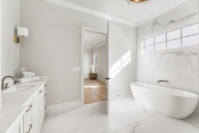 bathroom with a bathtub, vanity, and ornamental molding