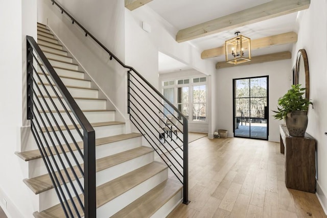 entryway with light hardwood / wood-style floors, beam ceiling, and an inviting chandelier