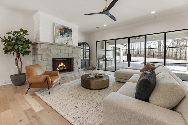 living room with a fireplace, ceiling fan, crown molding, and light hardwood / wood-style floors