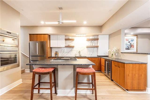 kitchen featuring wine cooler, sink, appliances with stainless steel finishes, a kitchen breakfast bar, and white cabinets