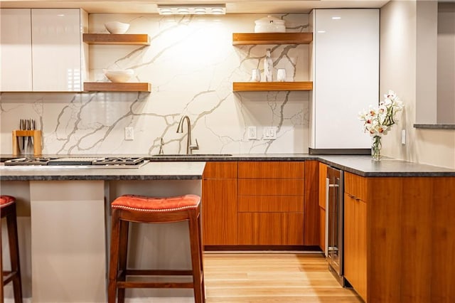 kitchen featuring white cabinetry, a kitchen breakfast bar, sink, and light wood-type flooring