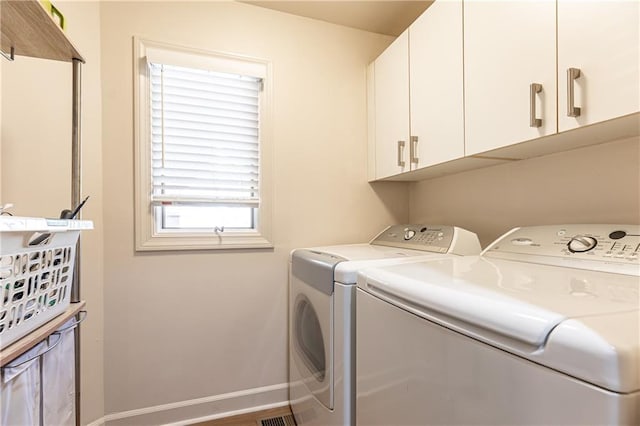 clothes washing area featuring separate washer and dryer and cabinets