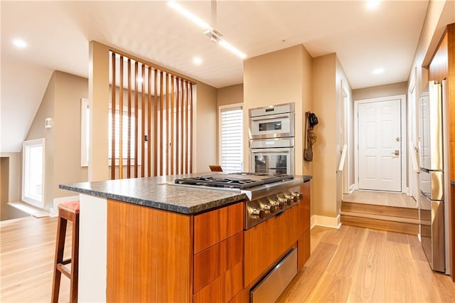 kitchen with stainless steel appliances, a center island, a breakfast bar, and light hardwood / wood-style flooring