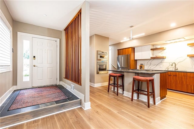 foyer entrance with a healthy amount of sunlight, sink, and light wood-type flooring