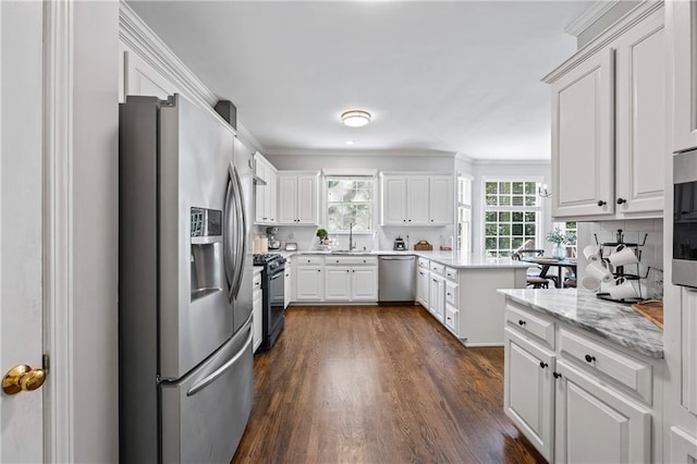 2500 Ashbourne Dr, Lawrenceville, GA 30043 - kitchen featuring appliances with stainless steel finishes, dark wood-style flooring, white cabinetry, a peninsula, and crown molding