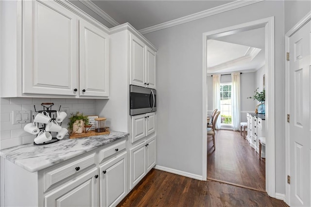 2500 Ashbourne Dr, Lawrenceville, GA 30043 - kitchen with stainless steel microwave, dark wood-type flooring, white cabinetry, backsplash, and ornamental molding